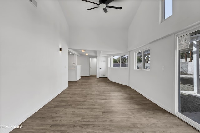 unfurnished living room with ceiling fan, high vaulted ceiling, wood finished floors, and baseboards