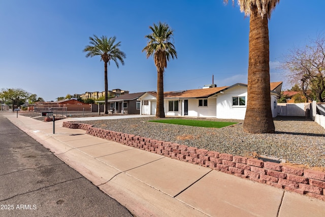 ranch-style home with roof mounted solar panels and fence