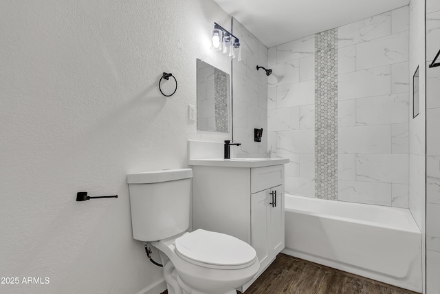 bathroom featuring a textured wall, bathtub / shower combination, toilet, wood finished floors, and vanity