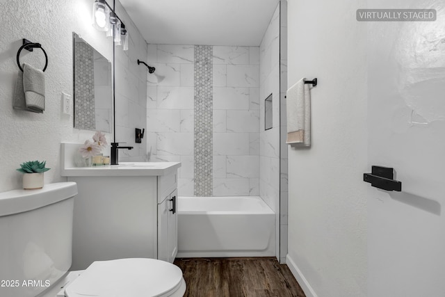 bathroom with a textured wall, toilet, wood finished floors, vanity, and washtub / shower combination