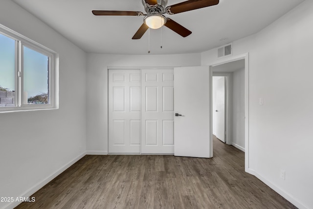 unfurnished bedroom featuring wood finished floors, a ceiling fan, visible vents, baseboards, and a closet