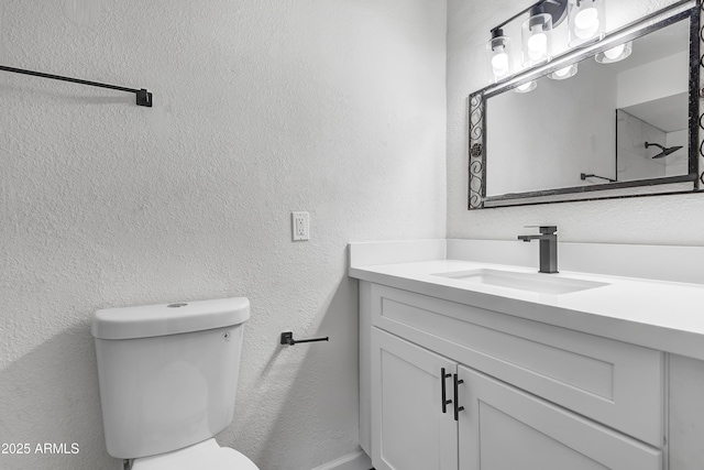 bathroom featuring a textured wall, vanity, and toilet