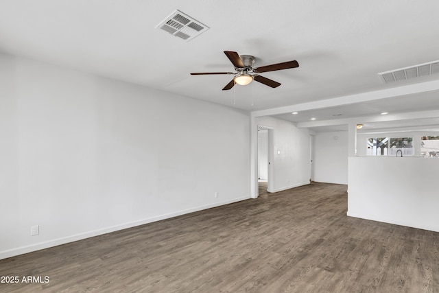 empty room with wood finished floors, visible vents, and baseboards