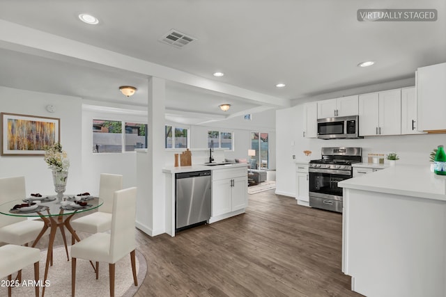 kitchen featuring recessed lighting, stainless steel appliances, a sink, light countertops, and dark wood-style floors