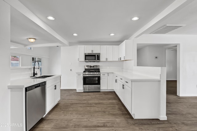 kitchen featuring stainless steel appliances, light countertops, visible vents, a sink, and a peninsula