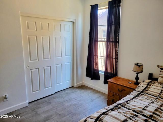 bedroom with baseboards, wood finished floors, and a closet