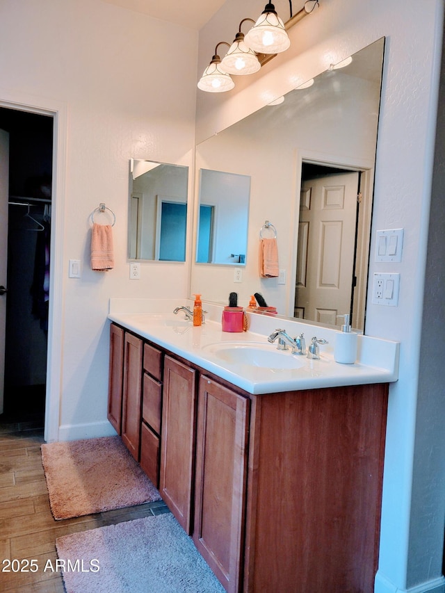 full bathroom featuring double vanity, baseboards, a sink, and wood finished floors