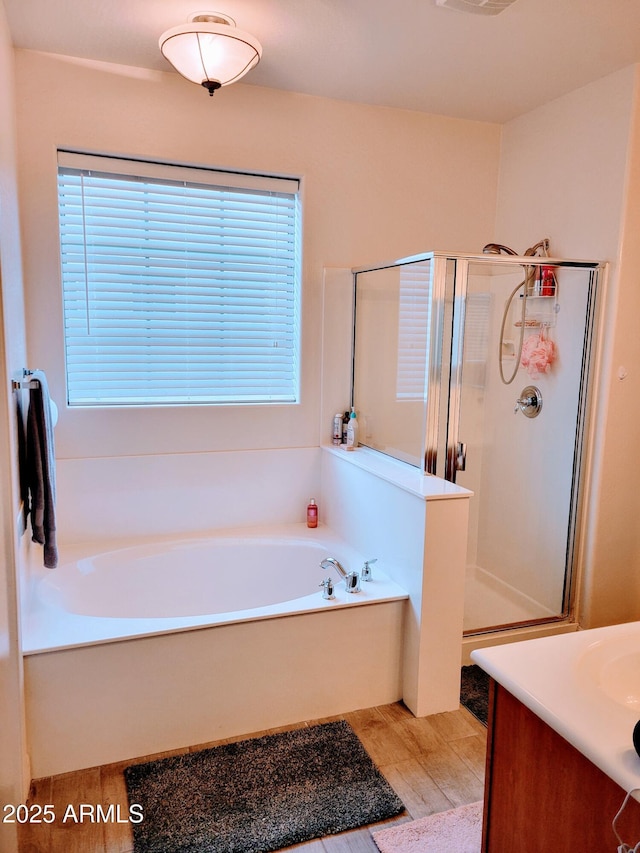full bathroom featuring vanity, a shower stall, a garden tub, and a wealth of natural light