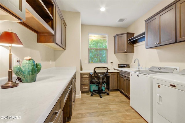 clothes washing area featuring washing machine and dryer, cabinets, and light hardwood / wood-style floors