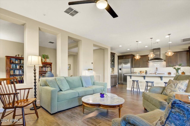 living room featuring ceiling fan, sink, and light hardwood / wood-style floors