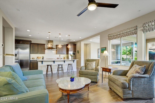 living room with light hardwood / wood-style flooring, ceiling fan, and sink