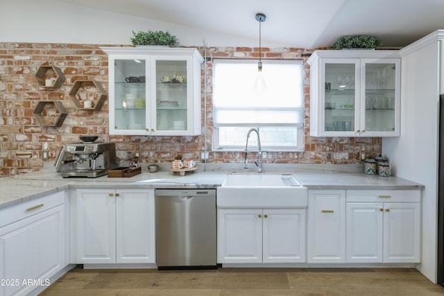 kitchen featuring lofted ceiling, sink, white cabinetry, stainless steel dishwasher, and pendant lighting