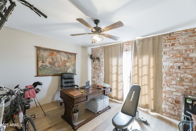 office space featuring ceiling fan, brick wall, and light wood-type flooring