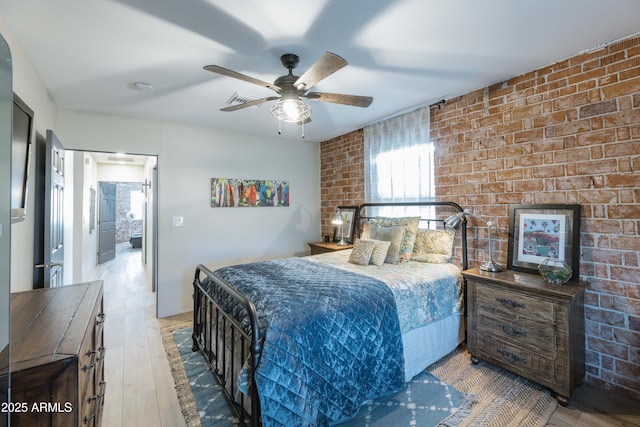 bedroom with ceiling fan, brick wall, and light hardwood / wood-style floors