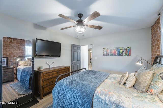 bedroom featuring ceiling fan, brick wall, and light wood-type flooring