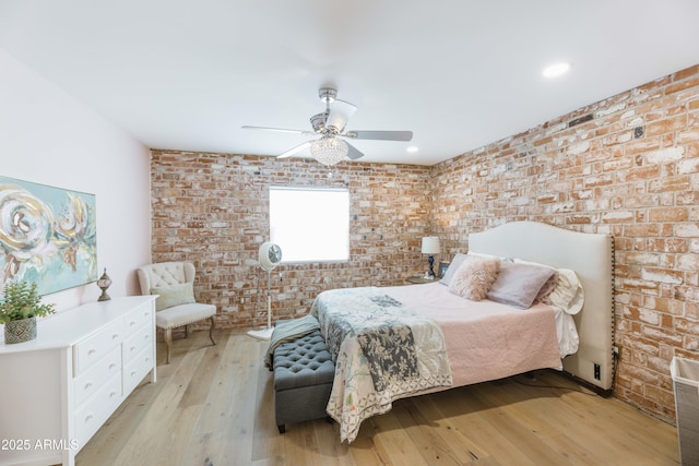 bedroom with ceiling fan, brick wall, and light wood-type flooring