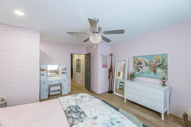 bedroom with ceiling fan, brick wall, and light hardwood / wood-style flooring