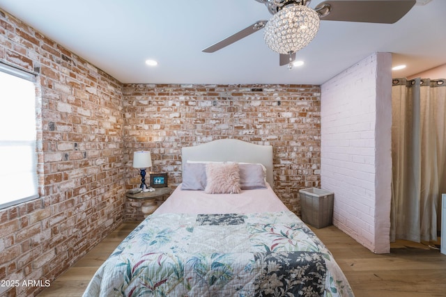 bedroom featuring ceiling fan, brick wall, and light wood-type flooring