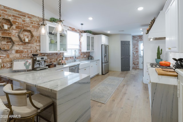 kitchen with hanging light fixtures, white cabinetry, appliances with stainless steel finishes, and kitchen peninsula