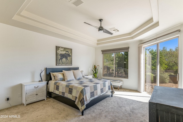 carpeted bedroom with access to outside, a tray ceiling, and ceiling fan