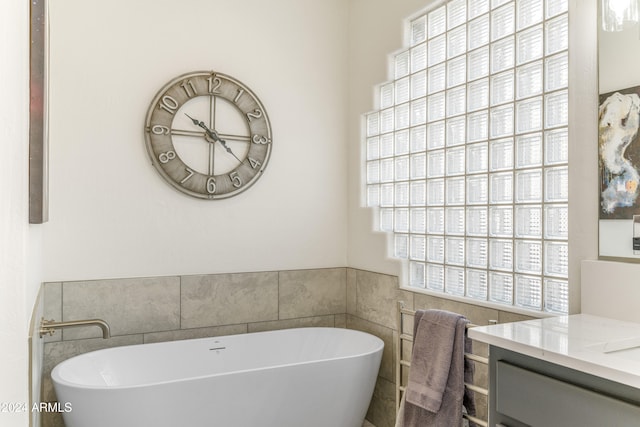 bathroom with vanity, a bathtub, and tile walls