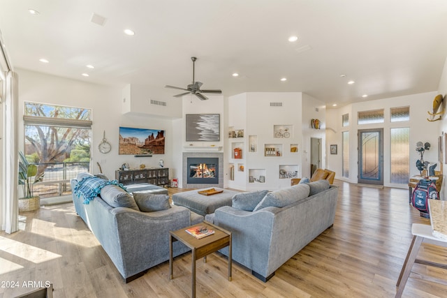 living room featuring a towering ceiling, ceiling fan, and light hardwood / wood-style flooring