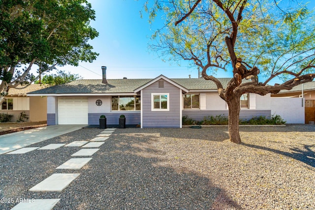 ranch-style home featuring a garage, concrete driveway, and a shingled roof