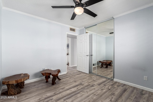 unfurnished bedroom featuring wood finished floors, baseboards, ornamental molding, a closet, and a textured ceiling