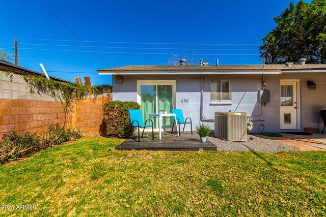 back of property with a yard, brick siding, central AC unit, and fence