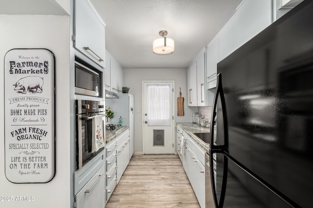 kitchen featuring light wood-type flooring, light countertops, appliances with stainless steel finishes, white cabinetry, and tasteful backsplash