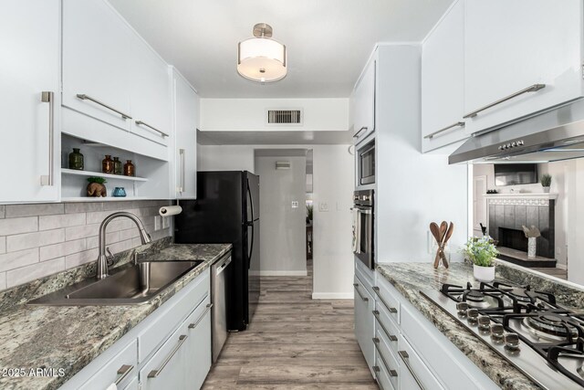 kitchen with visible vents, light wood finished floors, a sink, decorative backsplash, and stainless steel appliances