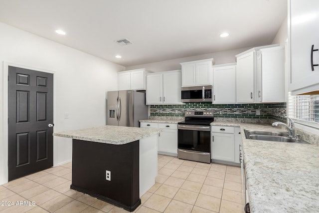 kitchen with sink, a center island, stainless steel appliances, light tile patterned floors, and white cabinets