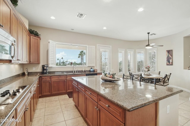 kitchen with a wealth of natural light, a center island, sink, and gas cooktop