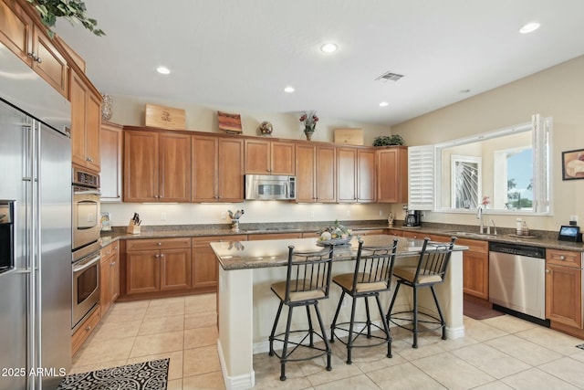 kitchen featuring sink, light tile patterned floors, a kitchen breakfast bar, stainless steel appliances, and a center island