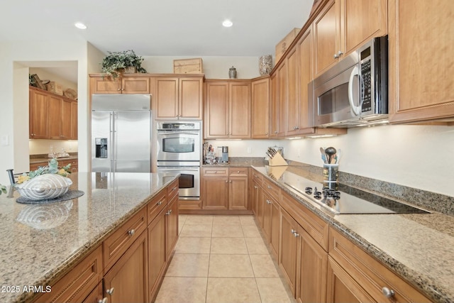 kitchen featuring stainless steel appliances, light stone countertops, and light tile patterned floors