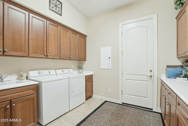 clothes washing area featuring sink, light tile patterned floors, washer and clothes dryer, electric panel, and cabinets