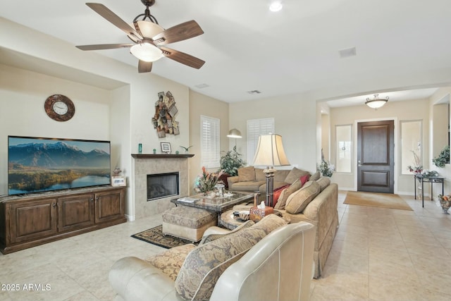 tiled living room featuring a tile fireplace and ceiling fan