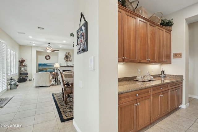 kitchen featuring light tile patterned floors, ceiling fan, and stone countertops