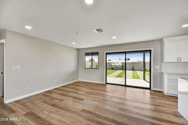 unfurnished living room featuring plenty of natural light and light wood-type flooring