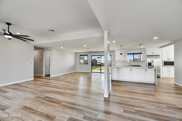 unfurnished living room with light hardwood / wood-style floors, ceiling fan, and sink