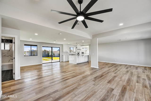 unfurnished living room featuring ceiling fan and light hardwood / wood-style floors