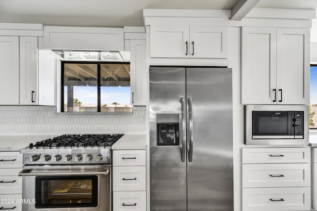 kitchen featuring decorative backsplash, appliances with stainless steel finishes, white cabinetry, and light stone countertops