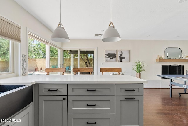 5912 E Wethersfield Rd, Scottsdale, AZ 85254 - kitchen with gray cabinets, light countertops, a peninsula, dark wood-style floors, and pendant lighting