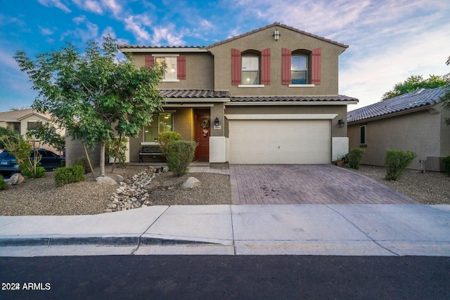 view of front of home with central AC unit and a garage