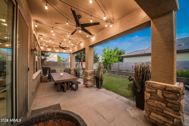 patio terrace at dusk with a yard and ceiling fan