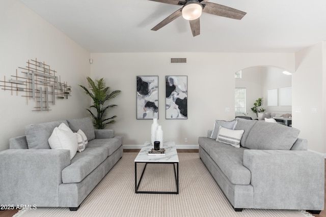 living room with arched walkways, ceiling fan, baseboards, and wood finished floors