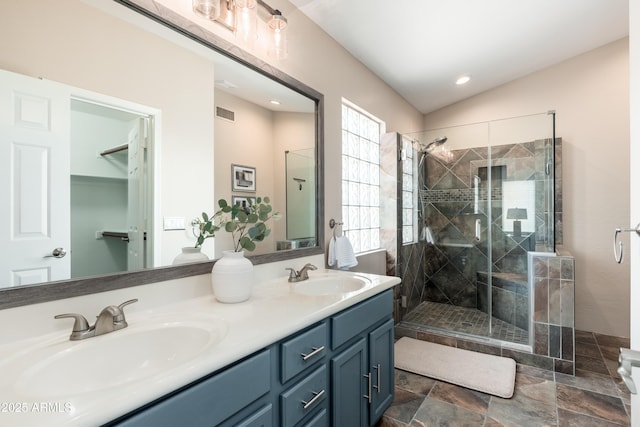 full bathroom with a stall shower, double vanity, stone finish floors, and recessed lighting