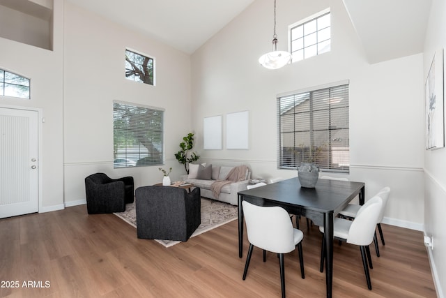 dining room with a towering ceiling, healthy amount of natural light, and wood finished floors