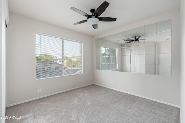 carpeted empty room featuring baseboards and ceiling fan