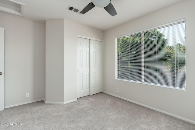 unfurnished bedroom with carpet flooring, a closet, baseboards, and a ceiling fan